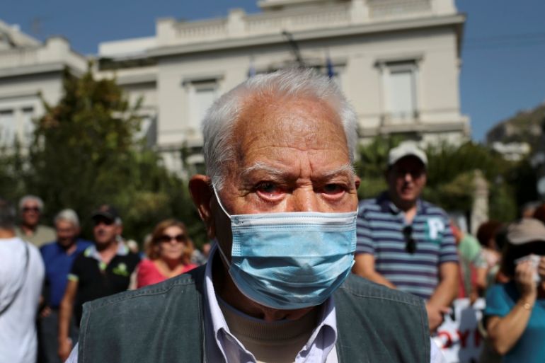 A Greek pensioner covers his face with a surgery mask after riot police used tear gas during a demonstration against planned pension cuts, in Athens
