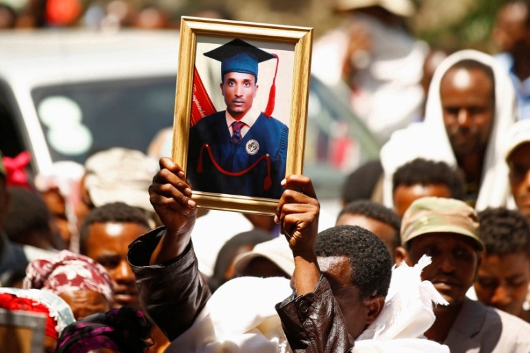 A man at a funeral holds up the portrait of Tesfu Tadese Biru
