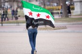 A woman carries a Syrian freedom flag in a park across the street from the White House in Washington DC [Getty]