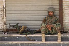An Afghan National Army soldier sits in front of a closed shop in the downtown of Kunduz city, Afghanistan [REUTERS]
