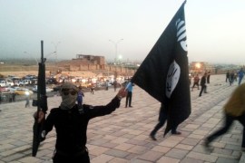 ISIL fighter holds a flag and a weapon on a street in Mosul