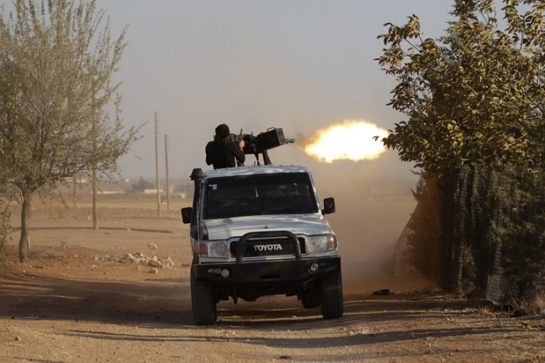 A rebel fighter shoots his weapon as they advance towards Azaz city