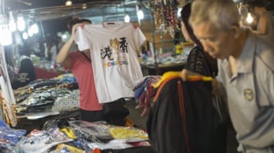 Tourists browse through T-shirts for sale in a night bazaar in Temple Street, Hong Kong, China [EPA]
