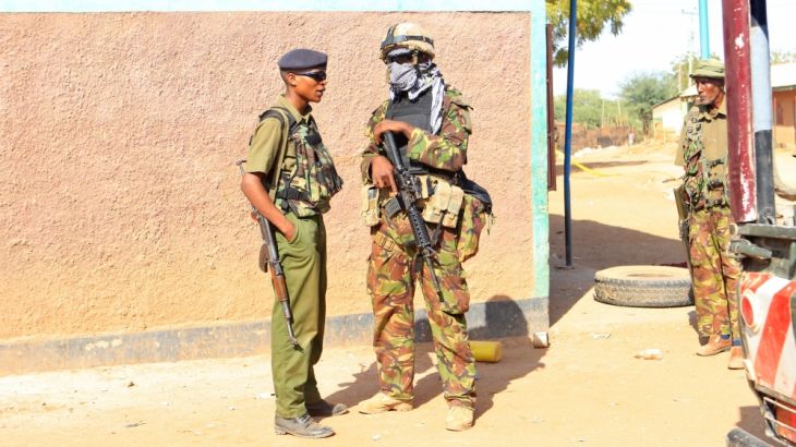 Kenya police and military stand near the scene of the destruction following an attack at the Bisharo lodging by Islamist militants from the Somali group al Shabaab in Mandera, Kenya