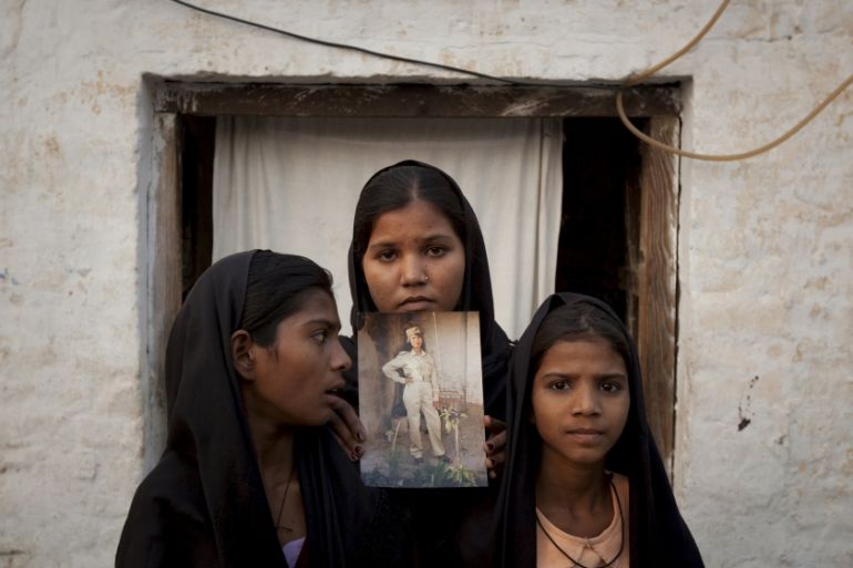 File photo of the daughters of Pakistani Christian woman Asia Bibi posing with an image of their mother while standing outside their residence in Sheikhupura Pakistan