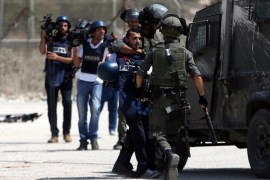 Israeli border policemen detain a Palestinian journalist during clashes with Palestinian protesters near Israel''s Ofer Prison near the West Bank city of Ramallah