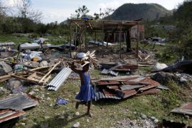 A girl carrying wood walks near debris after Hurricane Matthew passed, in Camp Perrin