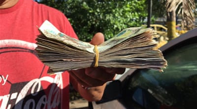 Dicson exchanged a trunkful of Venezuelan bolivars for a stack of Colombian pesos at the exchange office [Anne Bouleanu/Al Jazeera]