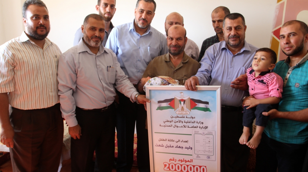 Jihad and Walid Shaat, along with relatives and interior ministry officials, celebrate Gaza's two-millionth resident [Ahmed Abdelal/Al Jazeera]