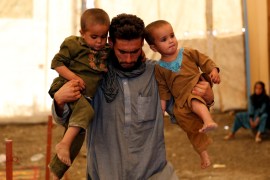 An Afghan man holds his children after arriving at a UNHCR registration centre in Kabul, Afghanistan [REUTERS]