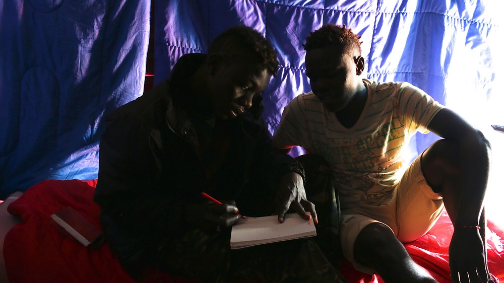 In the tent Idris has called home for the past month, he and Adam each write down the numbers of brothers they are trying to cross to the UK to reunite with [Caelainn Hogan/Al Jazeera]