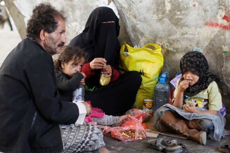 A homeless family eats lunch along a street in Sanaa, Yemen