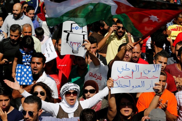 Jordanian protesters carry the Jordanian national flags, and chant slogans during a protest against a government agreement to import natural gas from Israel, in Amman