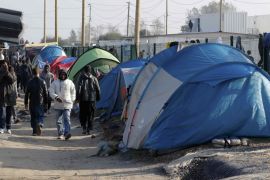Migrants walk in an alley near tents and makeshift shelters on the eve of the evacuation and dismantlement of the camp called the "Jungle" in Calais