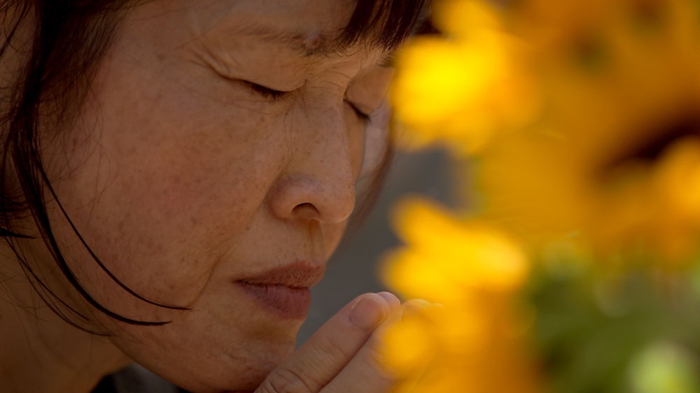 Keiko Aoki prays at her daughter's grave. She plans to sue the Japanese government after she served 20 years in prison for her daughter's murder [ Craig Hansen/Al Jazeera] 
