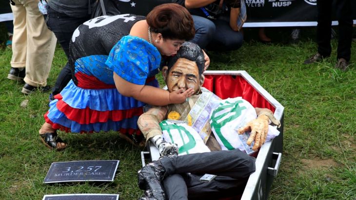 A protester impersonating former Philippine First Lady Imelda Marcos kisses an effigy of late dictator Ferdinand Marcos inside a mock coffin during a protest at Luneta park, metro Manila