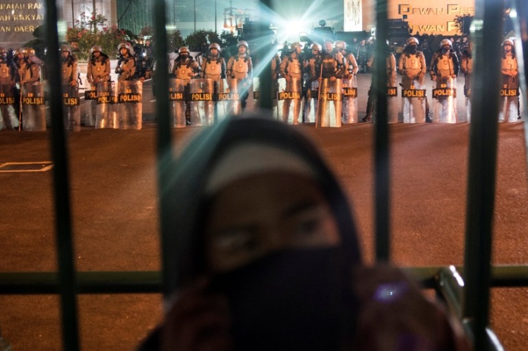 A hardline Muslim protester stands in front of Parliament building as policemen stand guard during a protest against Jakarta''s incumbent governor Basuki Tjahaja Purnama, an ethnic Chinese Christian ru