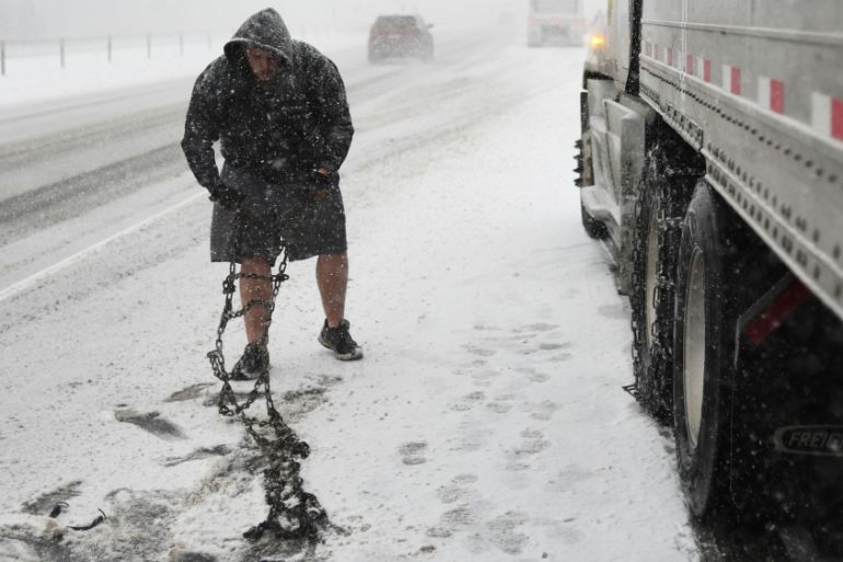 Truck driver Tim Swartz, wearing shorts, stop to fit snow chains on Interstate 70, Colorado, US