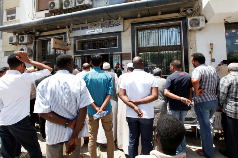 People queue to withdraw money at a bank in Tripoli