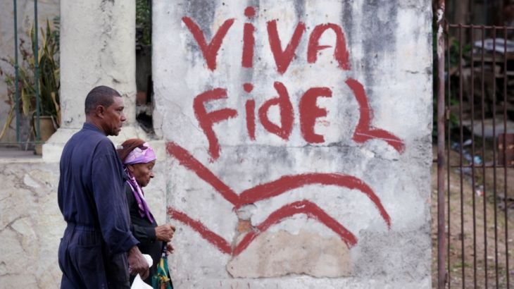 People walk past a graffiti that reads "Long live Fidel" in Havana, Cuba