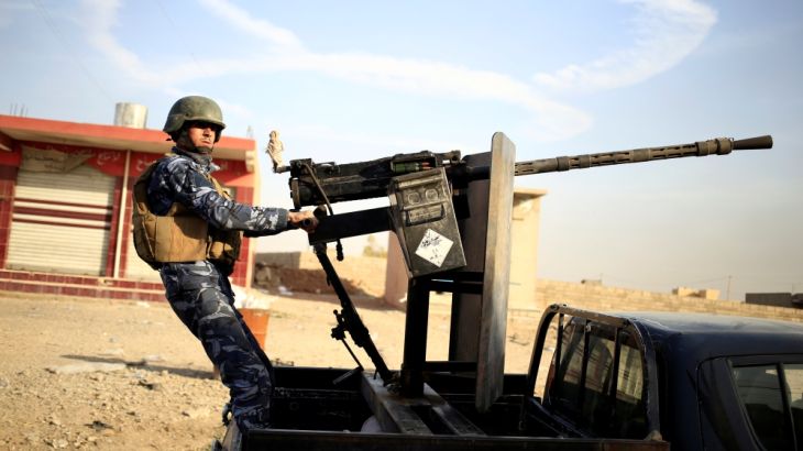 An Iraqi federal policeman aims his heavy machine gun on a vehicle in Samah district, eastern Mosul