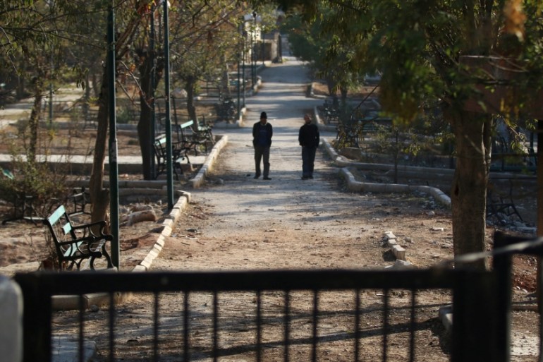 Men walk in a public park in a rebel-held besieged area in Aleppo