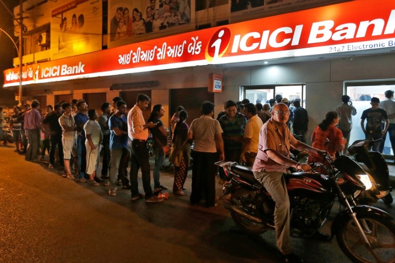 People wait to deposit and withdraw their money outside an ICICI Bank ATM in Rajkot