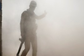 An Iraqi soldier walks through dust in a village outside Mosul