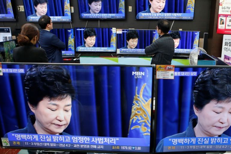 Employees watch TV sets broadcasting a news report on South Korean President Park Geun-hye releasing a statement to the public in Seoul, South Korea