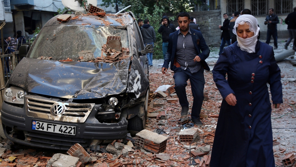 People walk past a damaged car after a blast in the Kurdish-dominated southeastern city of Diyarbakir [Sertac Kayar/Reuters]