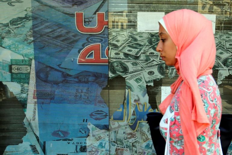 A woman walks past a money exchange bureau in Cairo