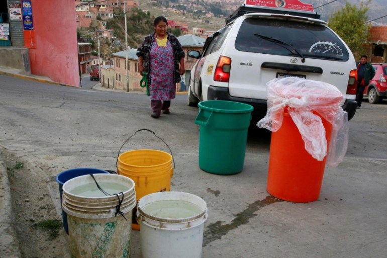 A woman prepares to load a car with buckets of water in Kupini, La Paz