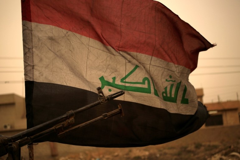 Iraq''s flag is seen during a sand storm in Bartilla, east of Mosul