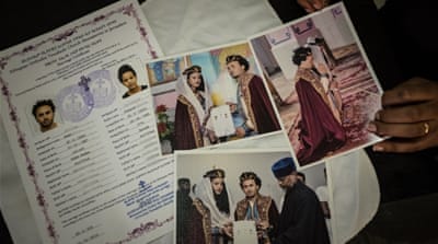 Ksenet displays photos and documents of the couple's wedding [Violeta Moura/Al Jazeera]