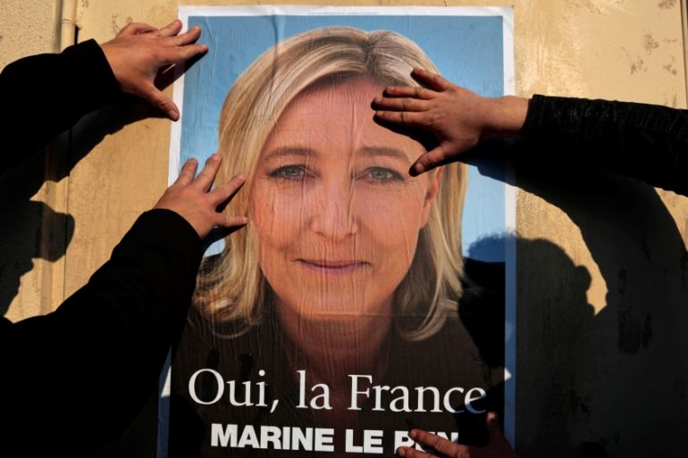 Supporters paste a poster of Marine Le Pen, France''s National Front leader, on a wall before a political rally for local elections in Frejus