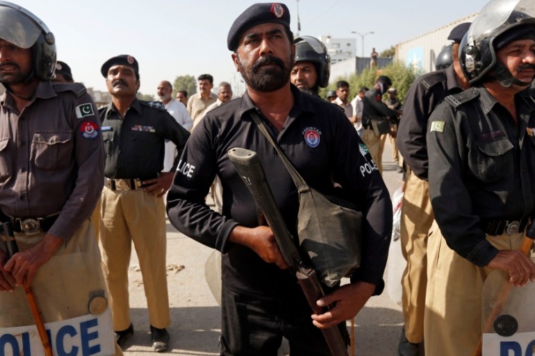 Police stand guard as Shi''ite Muslim men blocked the main national highway and railway tracks to protest the detention of their religious workers in Karachi