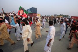 Supporters of Pakistani opposition leader Imran Khan run from tear gas as clashes begin between police and protesters in Swabi