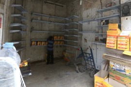 A boy inspects boxes inside a grocery shop with low supplies in the rebel-held besieged area of Aleppo