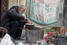 A man cooks a meal using firewood in Aleppo