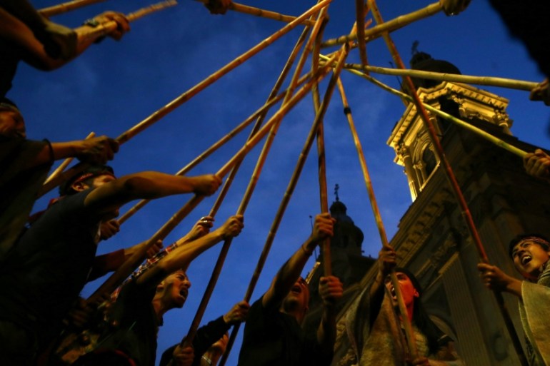 Mapuche Indian activists raise their sticks during a demonstration to demand justice for indigenous Mapuche inmates as well as for their indigenous rights and land for their communities in Santiago