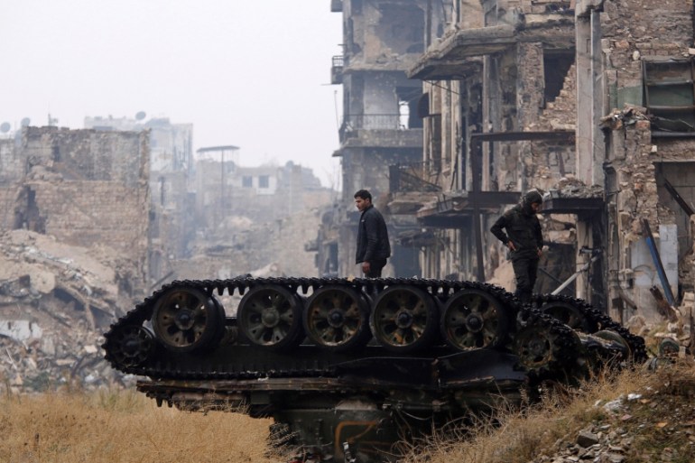 FILE PHOTO: Forces loyal to Syria''s President Bashar al-Assad stand atop a damaged tank near Umayyad mosque, in the government-controlled area of Aleppo, during a media tour, Syria