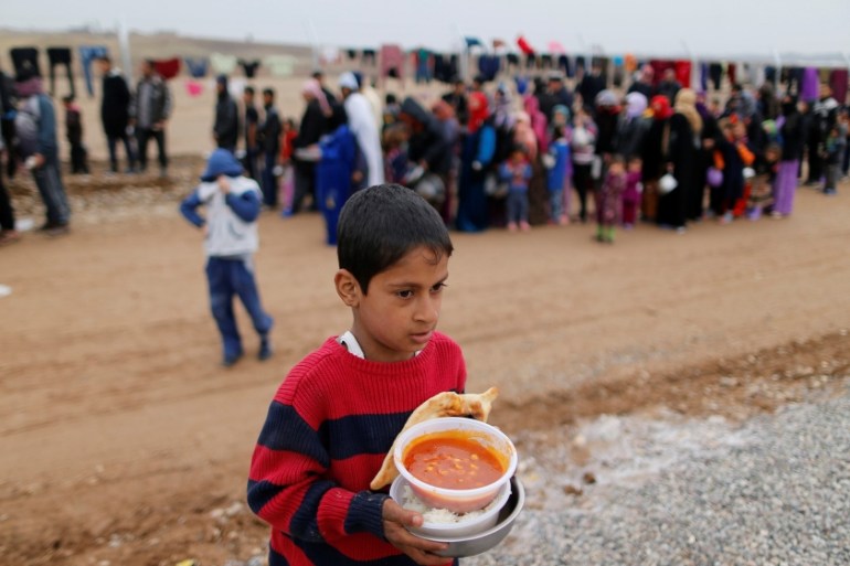 A boy who fled the Islamic State stronghold of Mosul, carries food at a refugee camp