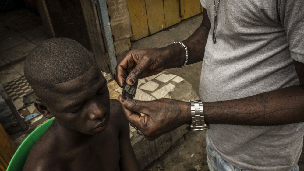  Kris Bitenda, with one of his clients at his barbershop, where he also draws tattoos, in the Lubugi district in Kinshasa  [Francesca Volpi/Al Jazeera] 