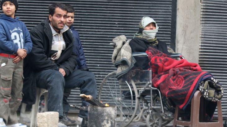 People warm themselves around a fire while waiting to be evacuated from a rebel-held sector of eastern Aleppo