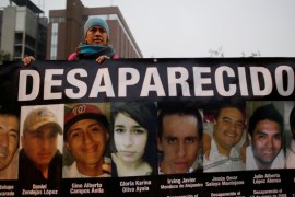 A demonstrator holds a banner with images of her relative and others, who they say went missing or were killed, during a demonstration demanding justice for the victims of violence, in Monterrey