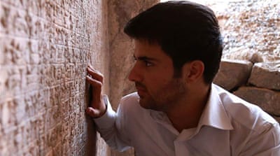 Hamza al-Fakhry examines the cuneiform writing at the palace of Assyrian King Sennacherib a few days before ISIL overran the city in 2014, prompting him to flee to Turkey [Courtesy of Hamza al-Fakhry/Al Jazeera]