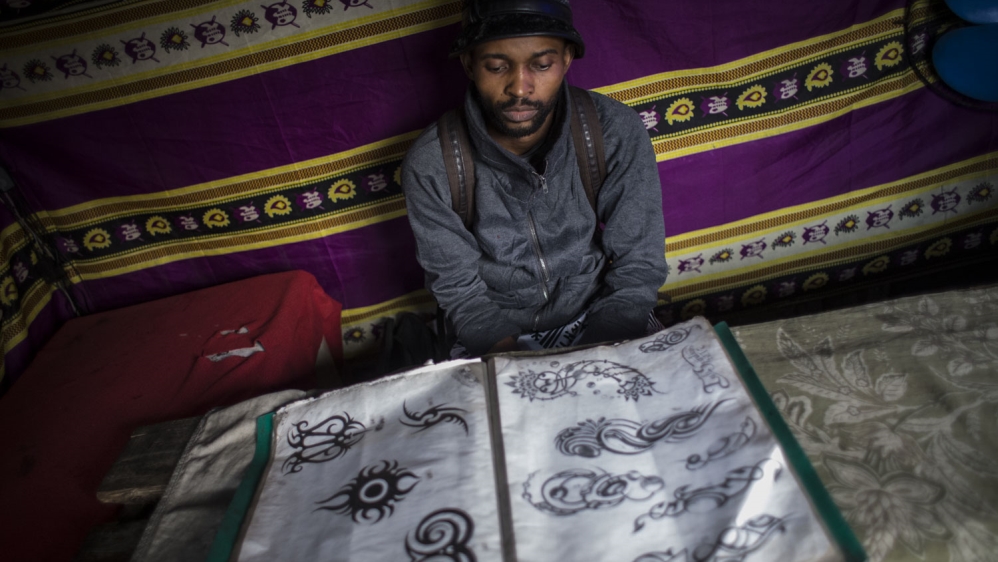A tattoo artist shows a catalogue of designs at his tattoo shop in the Lubugi district of Kinshasa [Francesca Volpi/Al Jazeera]