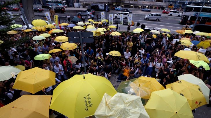 Pro-democracy protesters carrying yellow umbrellas stage a three-minute silence outside government headquarters in Hong Kong to mark the second anniversary of the movement