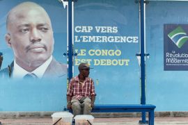 A vendor sits at a bus stand with pictures of Democratic Republic of Congo''s President Joseph Kabila in Kinshasa