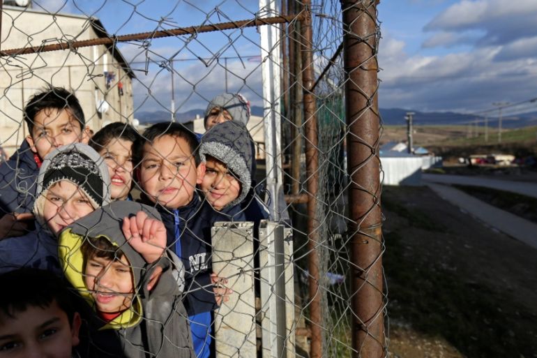 Roma children stand behind a fence near the so called "Sheffield Square" in the town of Bystrany